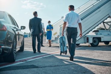 chauffeur-is-carrying-boss-luggage-while-walking-with-him-from-car-plane-pandemic_447912-6274