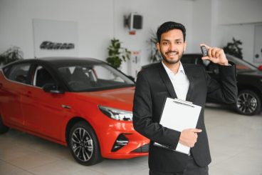 good-looking-cheerful-friendly-indian-salesman-poses-car-salon-showroom_255667-43173